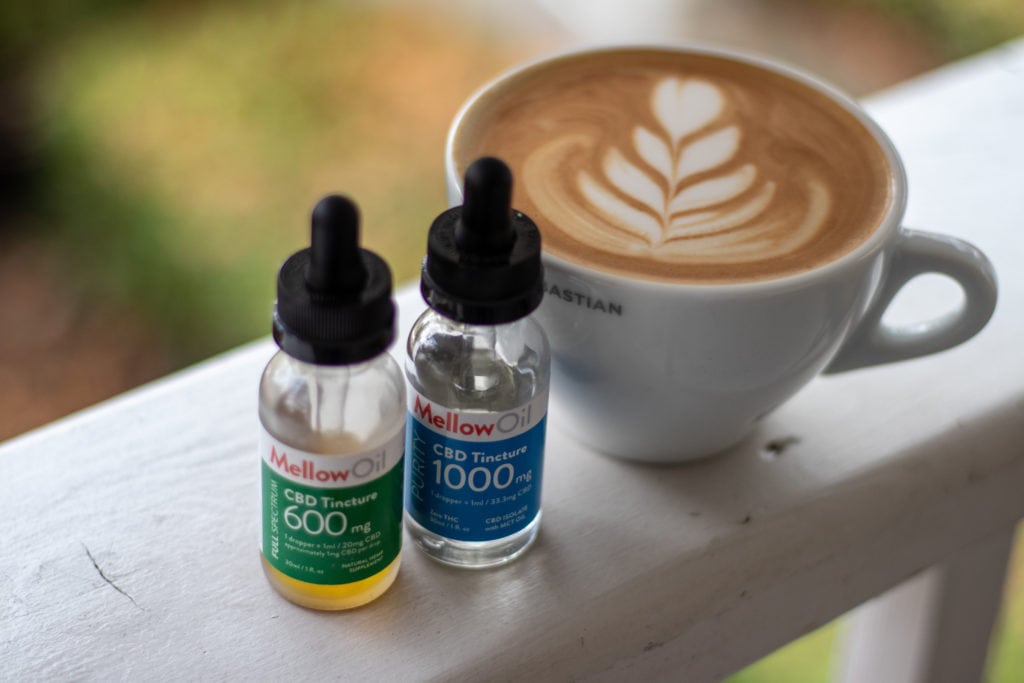 A CBD Oil infused latte with CBD Oil vials next to it.