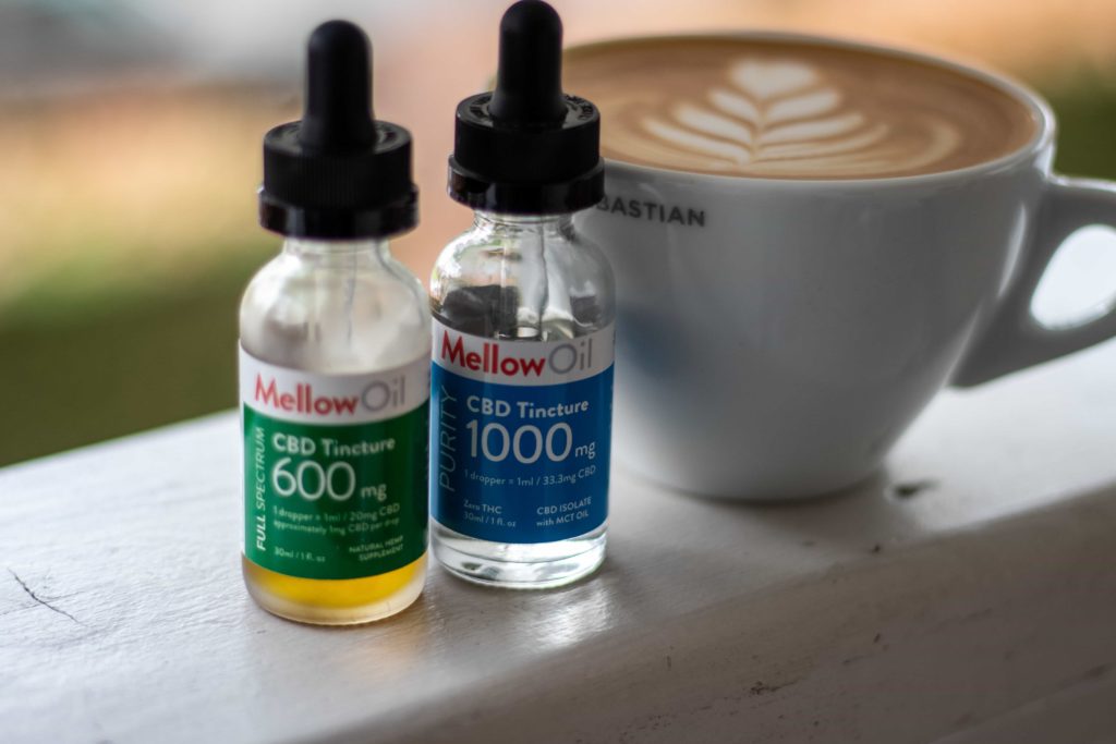 Two vials of CBD Oil next to a latte